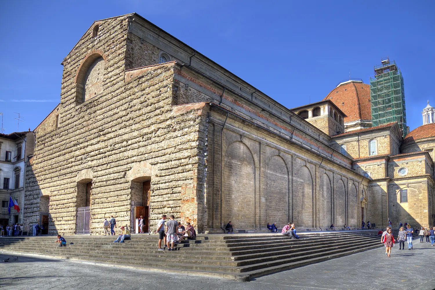 People sitting on the steps of the Basilica di San Lorenzo church in Florence, Italy