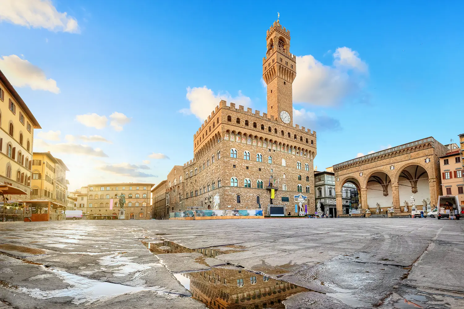 View of Piazza della Signoria square with Palazzo Vecchio reflecting in a puddle at sunrise in Florence, Italy